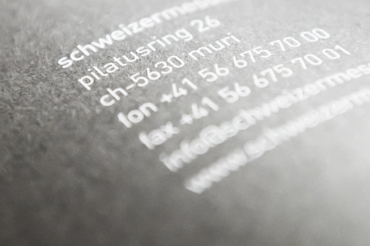 Bild der Adresse und Kontaktdaten von schweizermessebau auf einen Filz gedruckt.