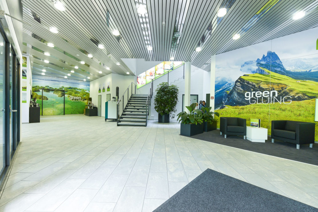 Ein Bild des Showrooms von Robatec mit grünem Hintergrund, grossen Grafiken und Treppe.